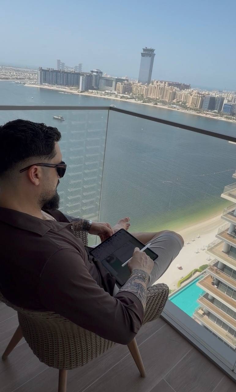 Ionut working on a tablet with a stylus on a balcony overlooking the sea